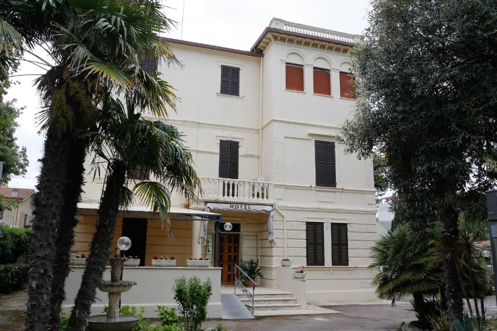 una casa blanca con palmeras delante en Hotel VILLA PINA, en Senigallia