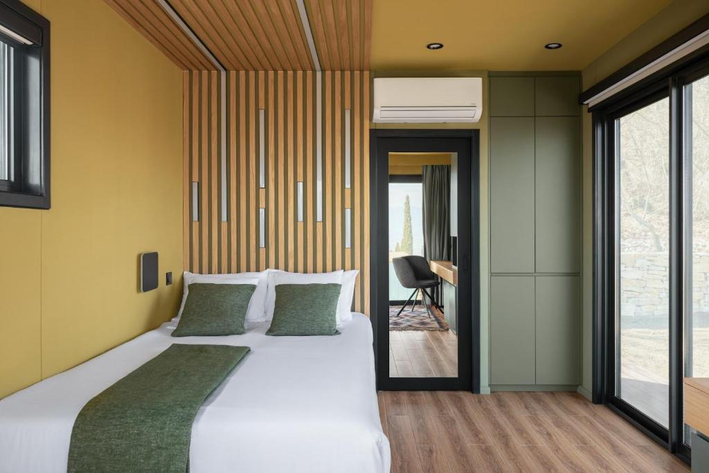 a bedroom with a large white bed with green pillows at Horizons Bakurtsikhe in Bakurtsʼikhe