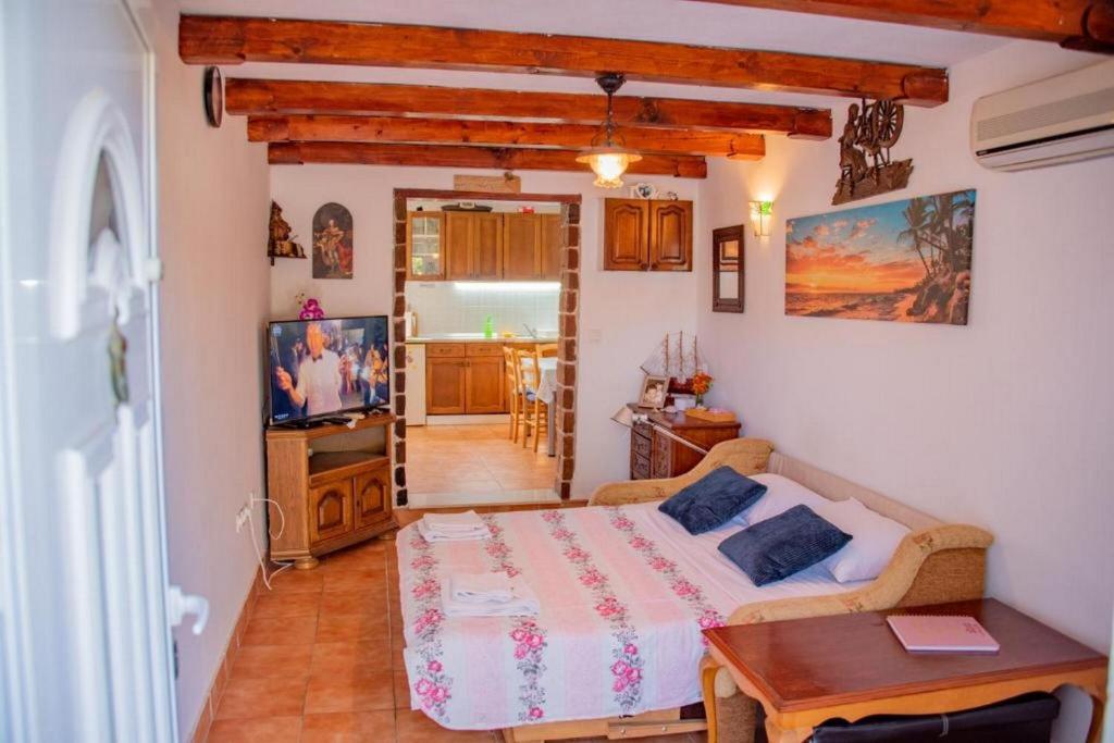 een slaapkamer met een bed, een tafel en een televisie bij House Matan in Tisno