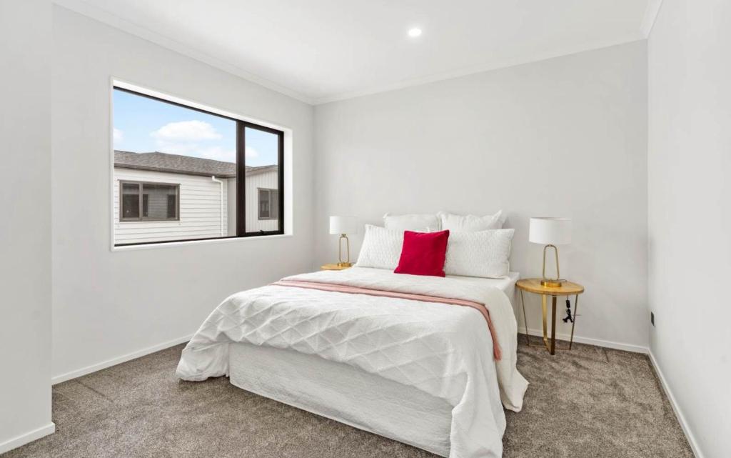 a white bedroom with a large bed and a window at Holiday Home at Huia Road in Auckland