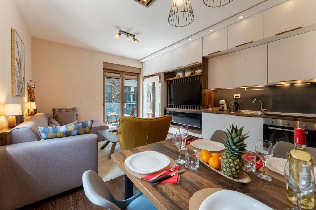 a kitchen and living room with a table and chairs at Zlatibor Centar Lux Apartman in Zlatibor
