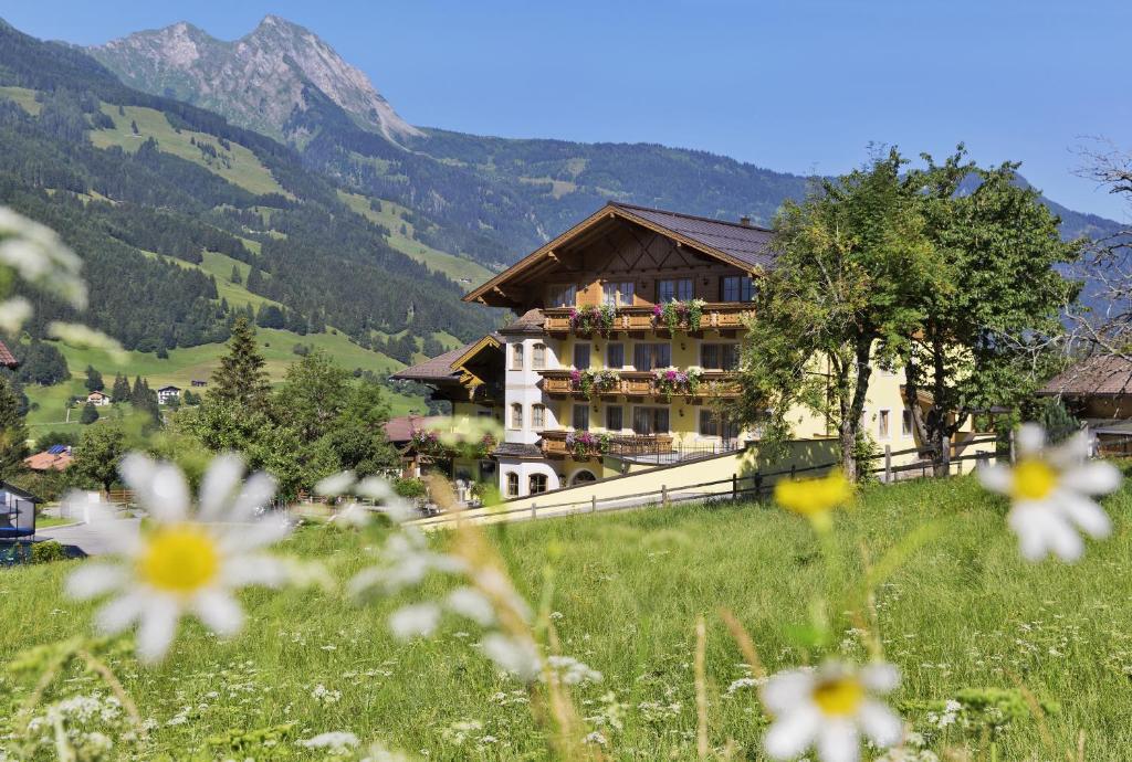 a building on a hill with flowers in the foreground at Landhotel Untermüllnergut in Dorfgastein
