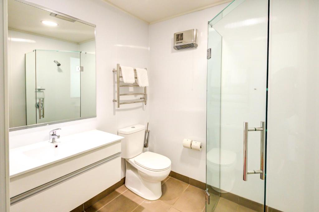 a bathroom with a toilet and a glass shower at Marakura Deluxe Motel in Te Anau