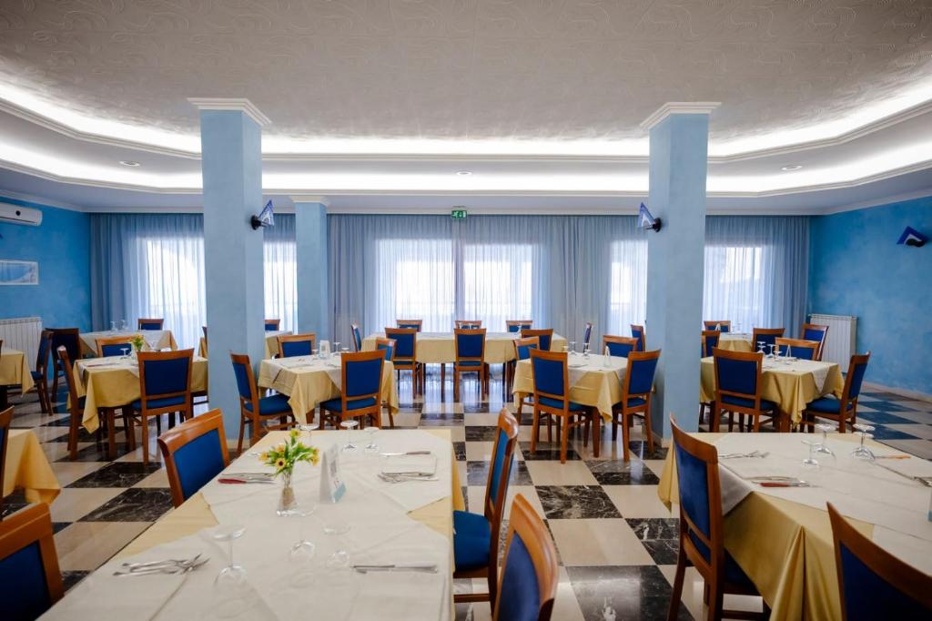 a restaurant with white tables and chairs and blue walls at Hotel Villa Principe in San Nicola Arcella