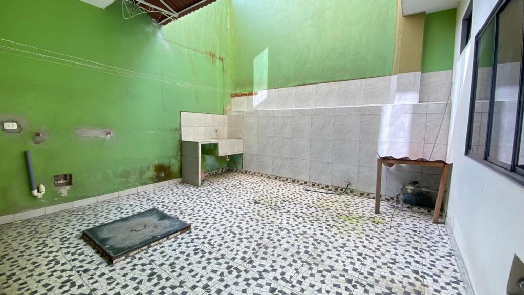 a bathroom with a green wall and a tiled floor at Casa Reátegui in Iquitos