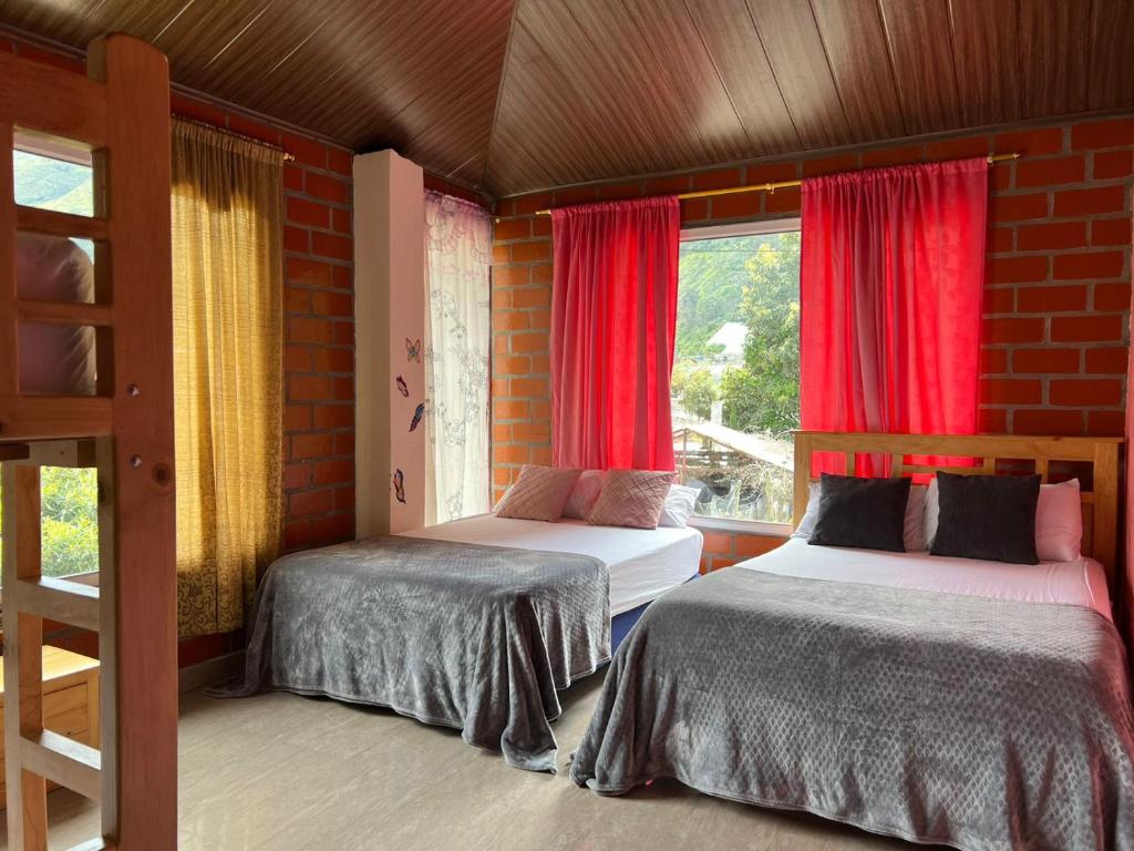 a bedroom with two beds and a window with red curtains at Holiday House - 3 Bedroom 3 Bathroom in Baños