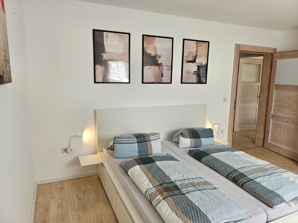 two beds in a room with three pictures on the wall at Apartment Home 2 in Schwabach