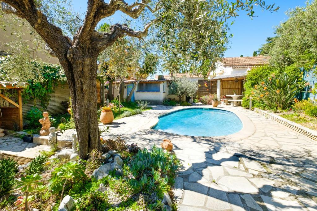 une cour avec une piscine et un arbre dans l'établissement Grand studio Bougainvillée, à Cagnes-sur-Mer