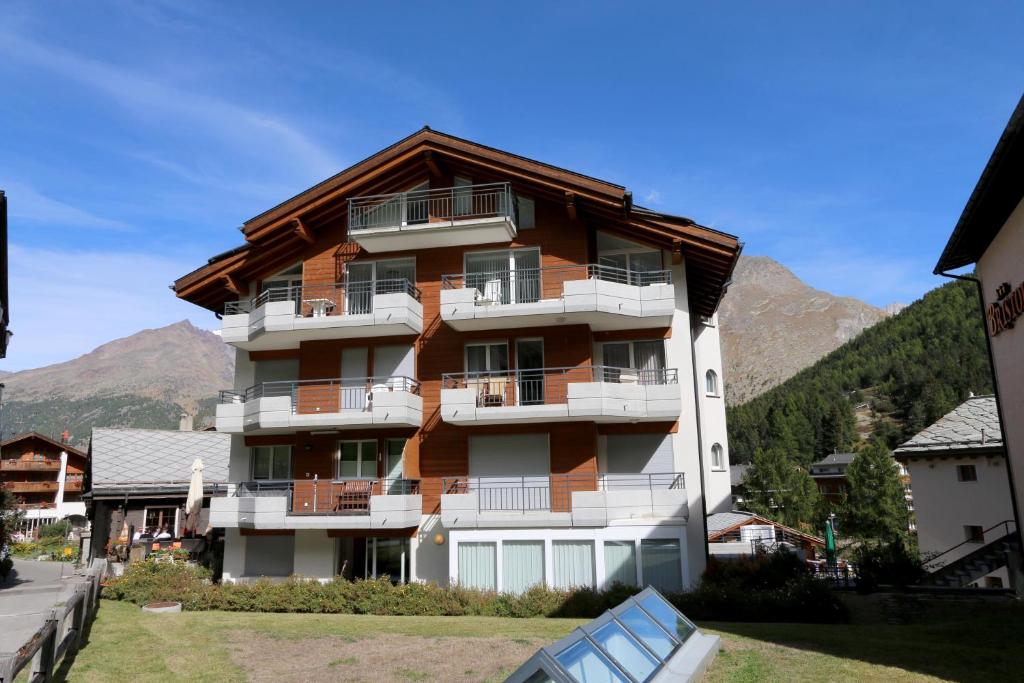 ein großes Apartmenthaus mit Bergen im Hintergrund in der Unterkunft Nicoletta in Saas-Fee