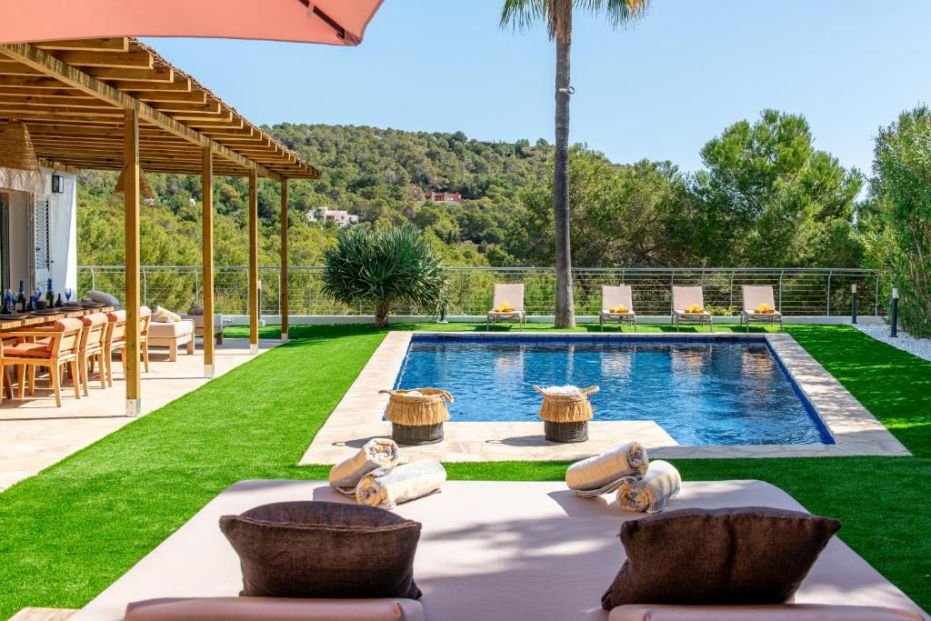 a backyard with a swimming pool with a table and chairs at Cap Martinet Talamanca Vila Can Tashellu, Boutique 5 bed - Sea and Forest View in Talamanca