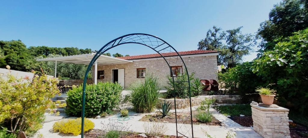 a garden with a garden arch in front of a house at Villa Romantica in Blato