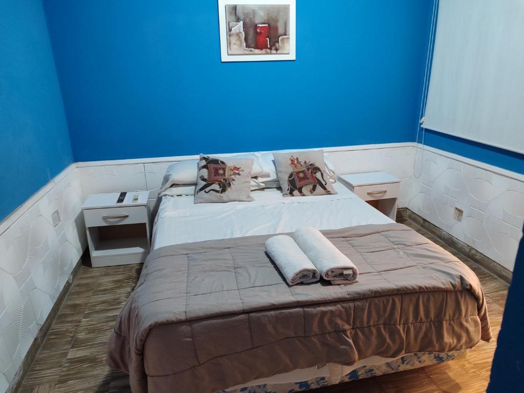 a blue room with a bed with towels on it at Pasaje Hotel in Aimogasta