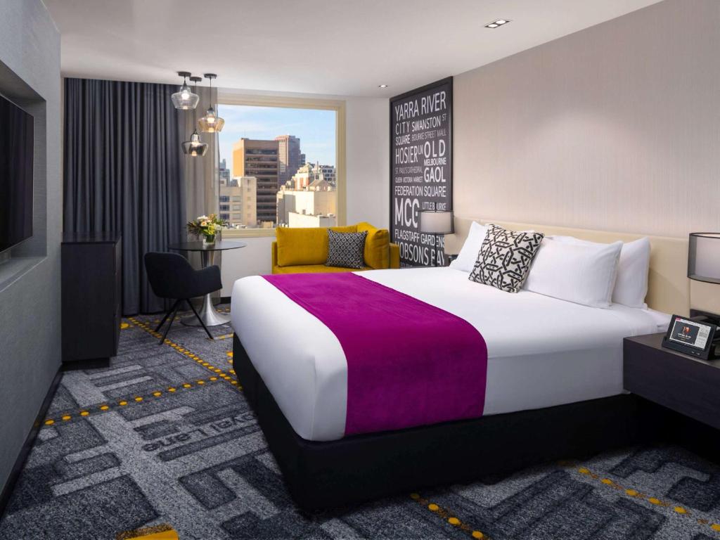 a hotel room with a large bed and a desk at Pullman Melbourne City Centre in Melbourne