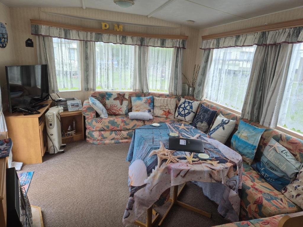 a living room with a couch and a table at Sandgate retreat hemsby 2023 in Hemsby