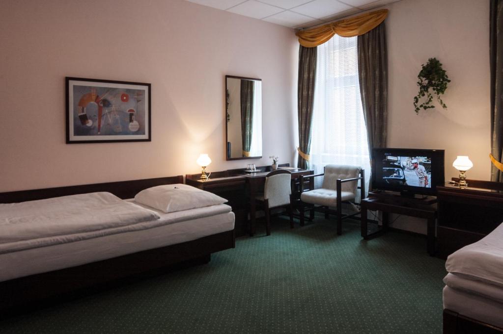 ブルノにあるホテル オメガ ブルノのベッド、デスク、テレビが備わるホテルルームです。