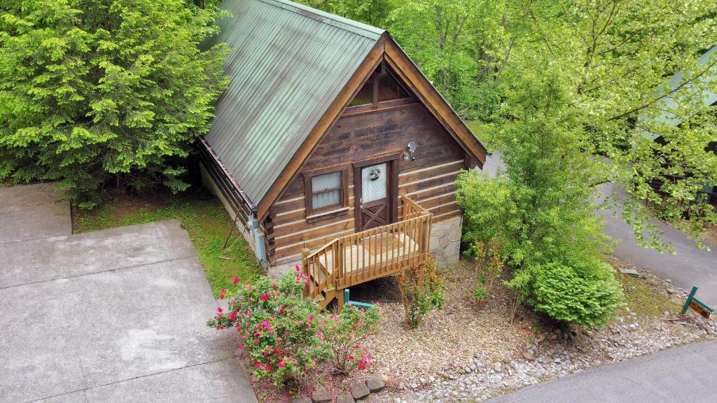 une vue de tête sur une cabine avec un banc et des fleurs dans l'établissement Cozy Cabin! Hot Tub, King Bed, Fireplace, & Pool, à Gatlinburg
