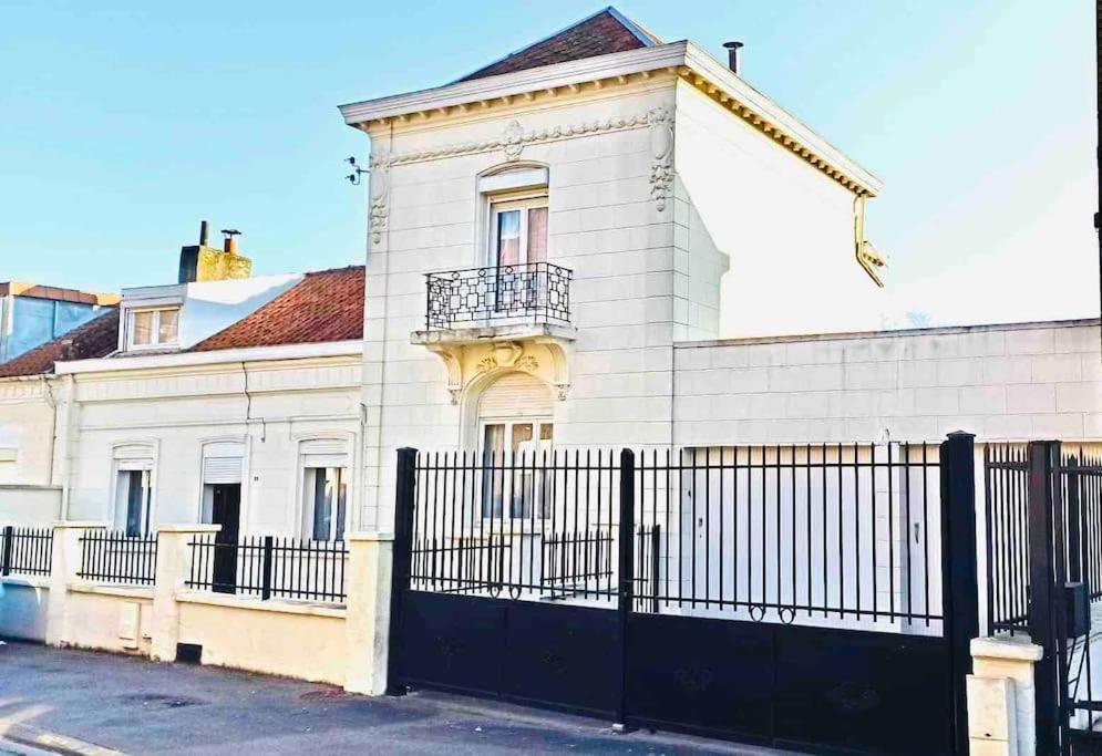 un bâtiment blanc avec une clôture devant dans l'établissement Maison chaleureuse 160 m2 avec grand jardin, à Anzin