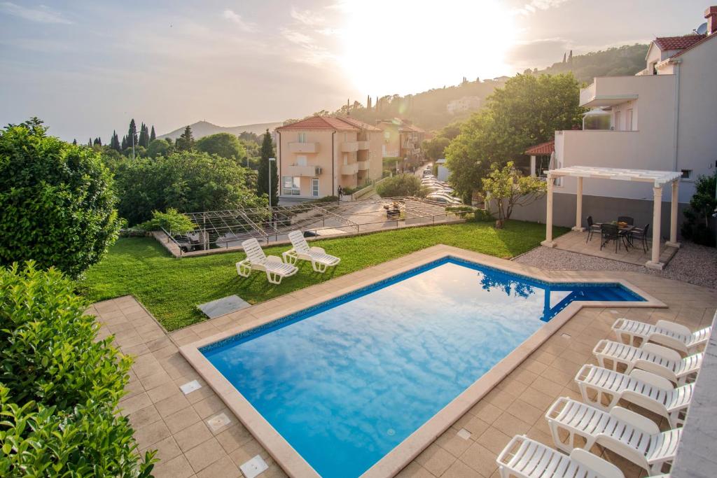 una piscina en un patio con sillas y una casa en Apartments Muller en Mlini