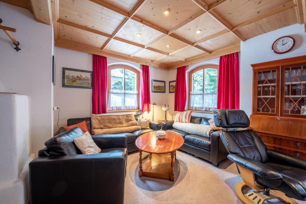 a living room with leather furniture and red curtains at Haus 34 Top 1 in Krimml