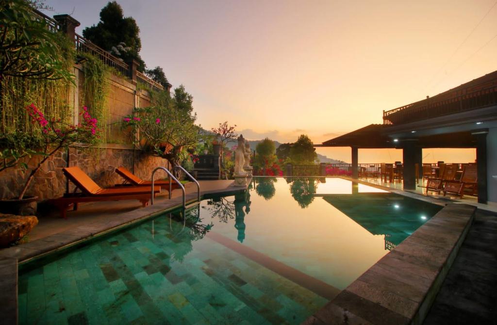 a swimming pool with two chairs next to a building at Rostika Hotel Sekumpul in Pabean Buleleng