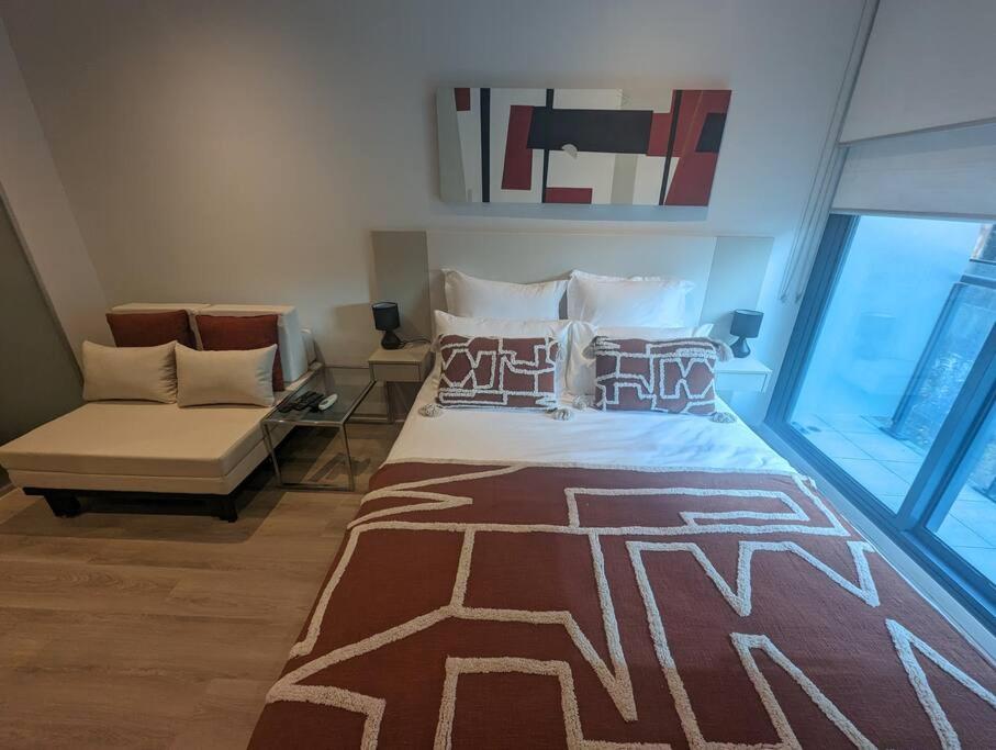 a bedroom with a bed and a couch in a room at Cosy City Studio Apartment in Melbourne