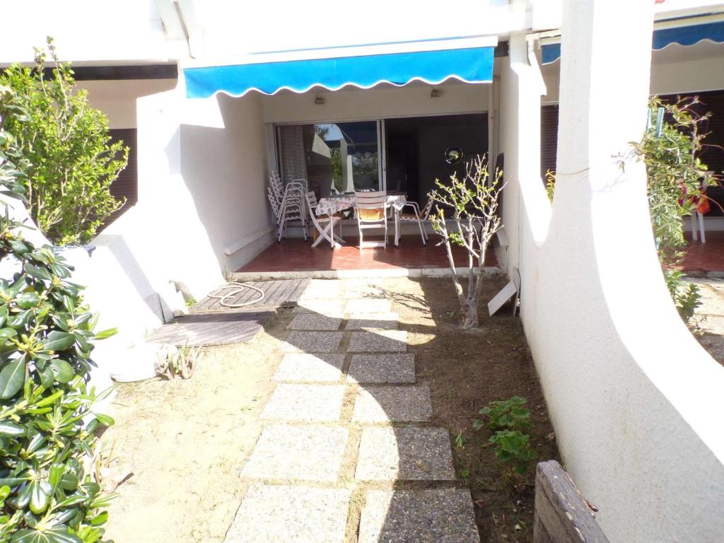 un patio avec une table et un auvent bleu sur une maison dans l'établissement Appartement 3 pièces avec loggia, jardin, accès direct plage, garage - La Grande-Motte - FR-1-328-111, à La Grande Motte
