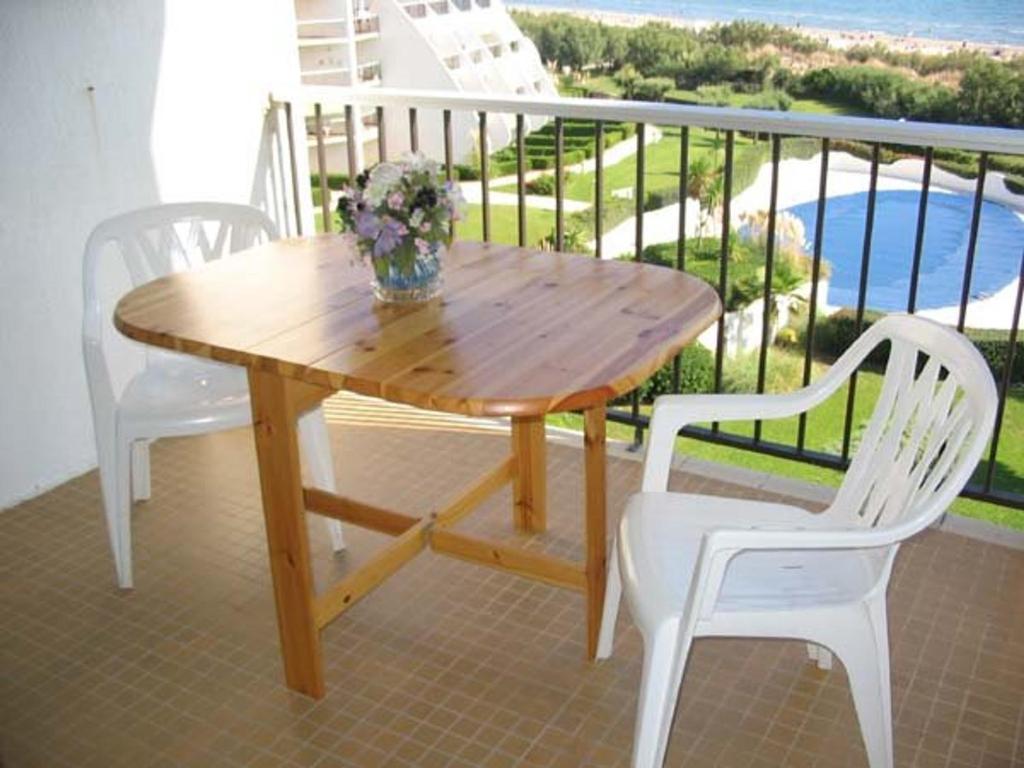 d'une table en bois et de 2 chaises blanches sur un balcon. dans l'établissement Studio Cabine avec Piscine sur la Plage, Parking, 21m², 4 Pers, La Grande Motte - FR-1-328-157, à La Grande Motte