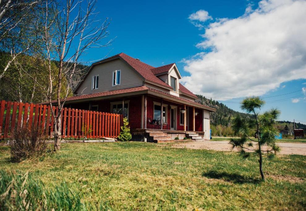 a house with a red fence in front of it at Le Chalet des Coteaux in LʼAnse-Saint-Jean