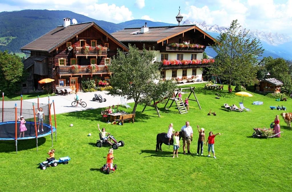 a group of people in a field in front of a house at Kinder-Bauernhof Ederbauer in Flachau