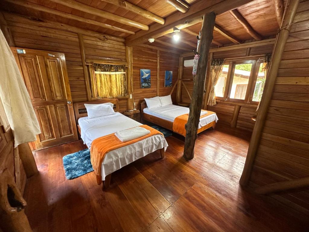 a bedroom with two beds in a wooden cabin at El Pajas in Puerto Velasco Ibarra