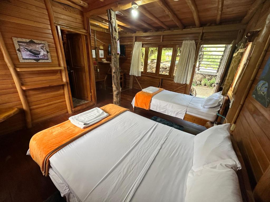 a bedroom with two beds in a wooden cabin at El Pajas in Puerto Velasco Ibarra