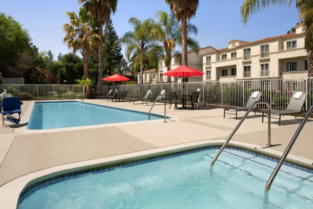 a swimming pool with chairs and umbrellas next to a building at Residence Inn Palo Alto Los Altos in Palo Alto