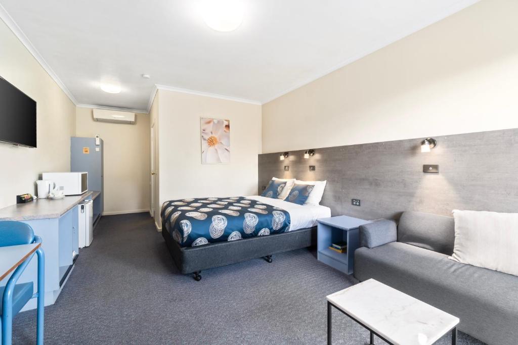um quarto de hotel com uma cama e um sofá em Colac Central Motel em Colac