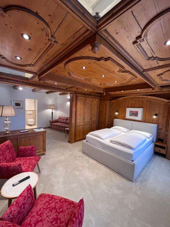 a bedroom with a bed and a couch and chairs at Hotel Spiegel Garni in Lindau