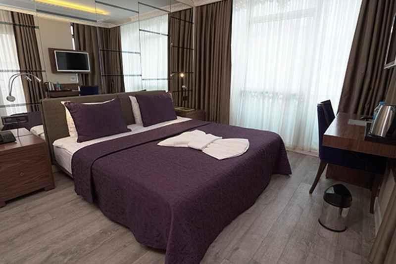 um quarto com uma cama roxa com toalhas em ATAKUM PALAS OTEL em Samsun