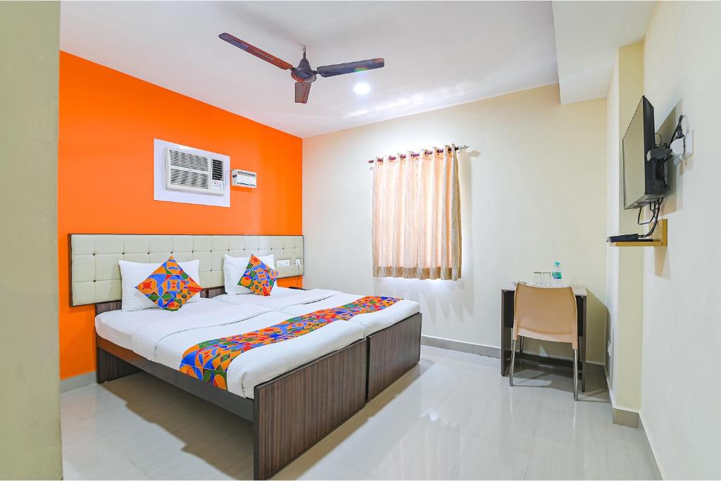 a bedroom with a bed with an orange wall at FabHotel VRJ Residency in Chennai
