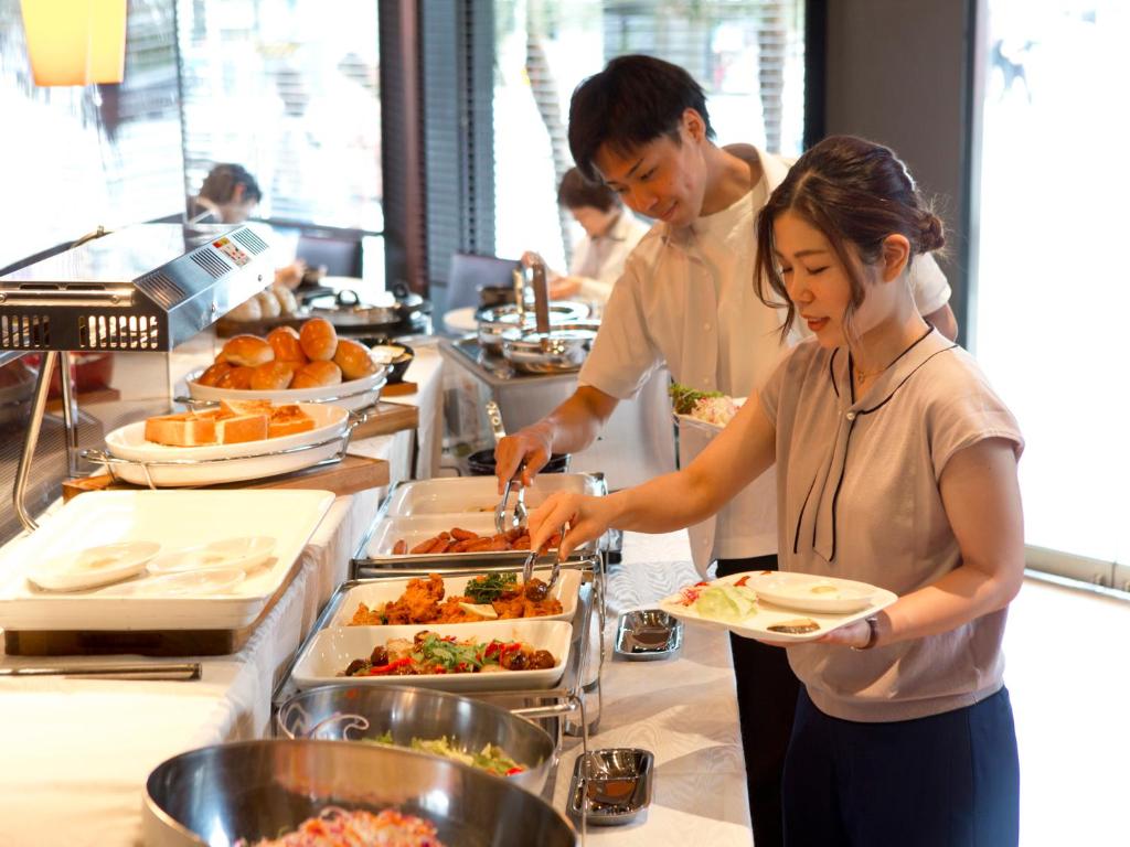 a man and a woman preparing food in a kitchen at Hotel Hillarys in Osaka