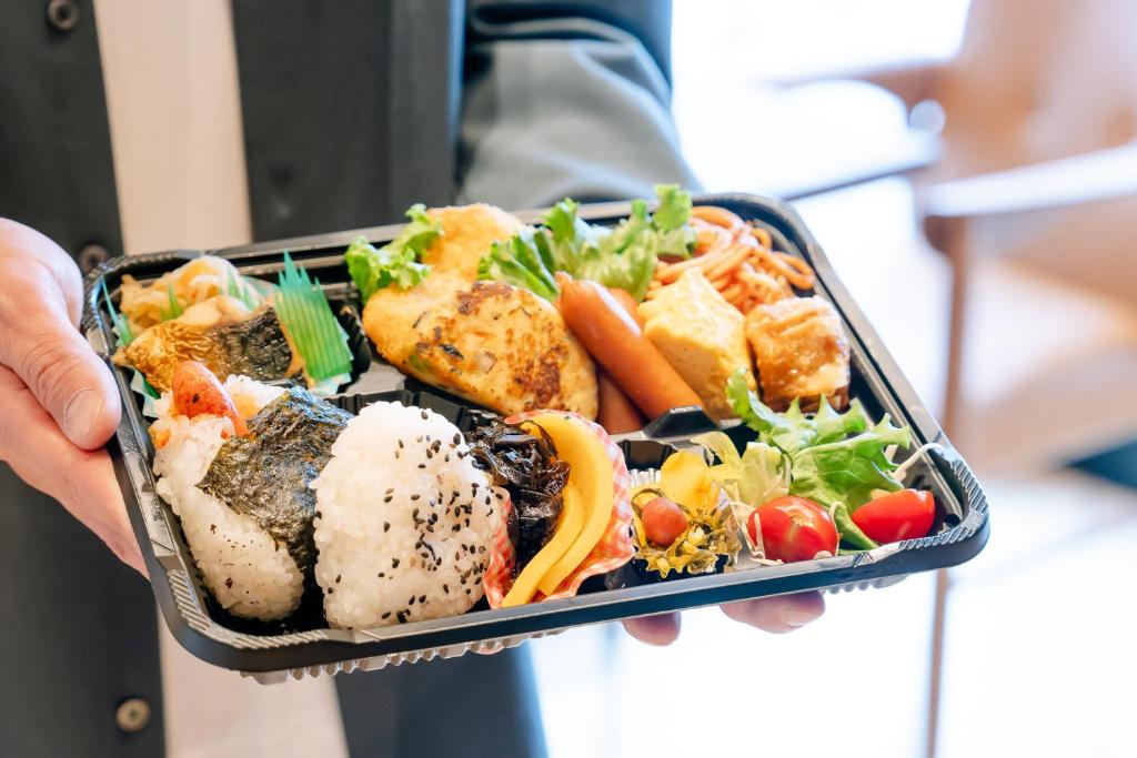 a person is holding a tray of food at Hotel Hillarys in Osaka