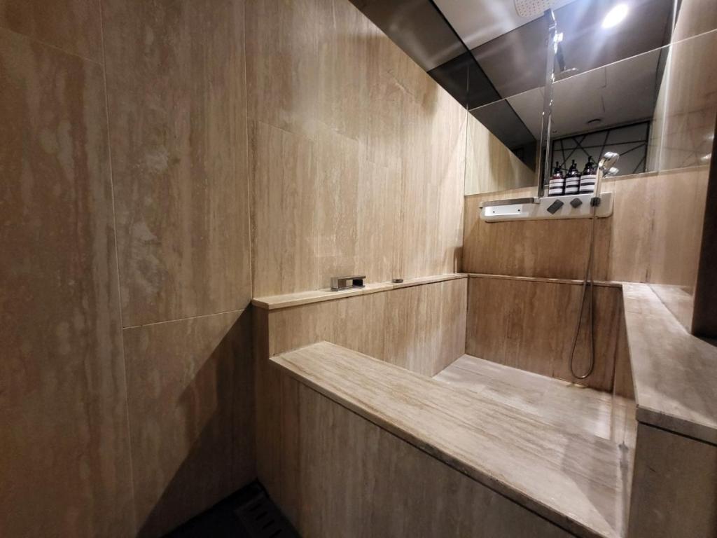 y baño con ducha y pared de madera. en Hotel Cullinan Wangsimni en Seúl