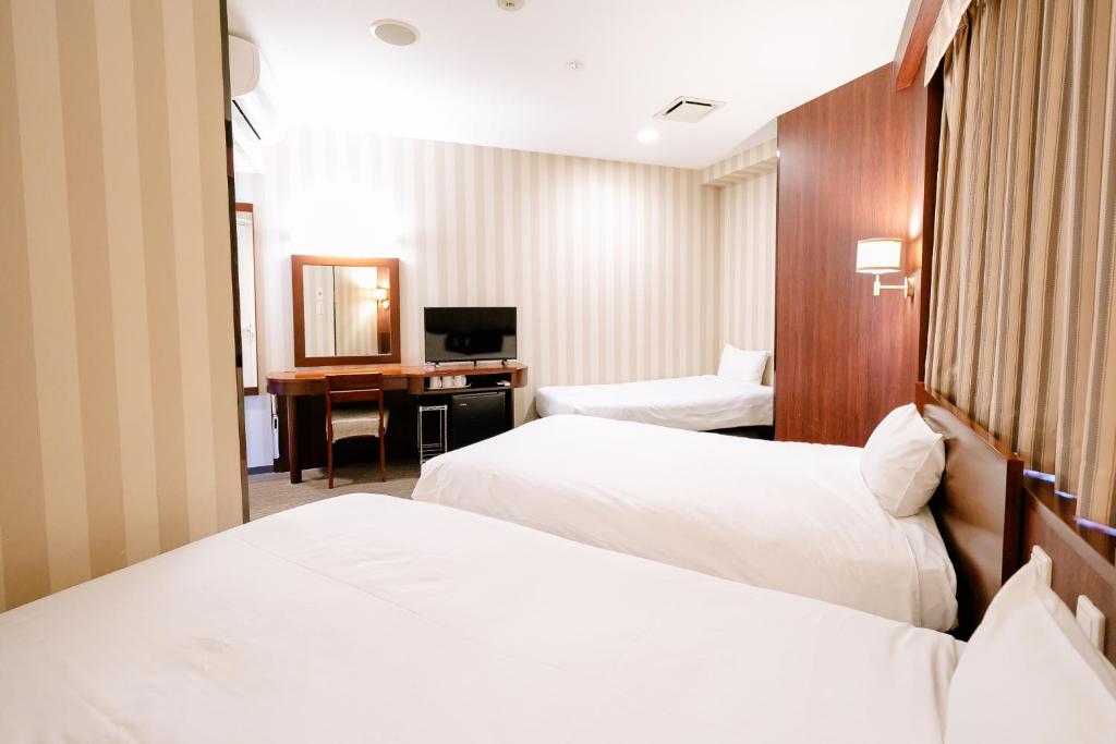 a hotel room with two beds and a desk at Hotel Hillarys in Osaka