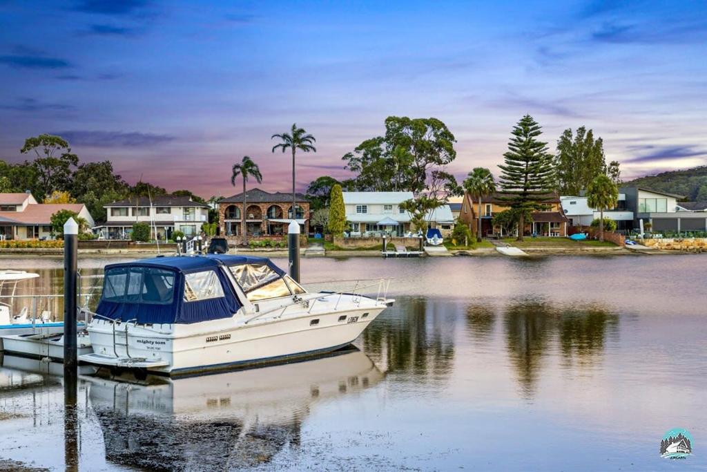 a boat is docked at a dock in the water at Aircabin - Woy Woy - Water Front - 6 Beds Lux Home in Daleys Point