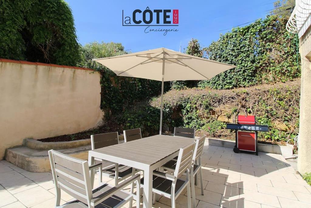 une table et des chaises avec un parasol et un grill dans l'établissement Picasso, à Sausset-les-Pins