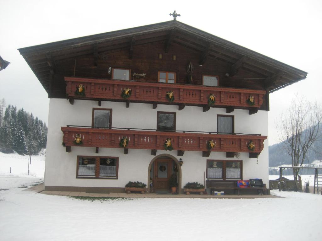 a building with a wooden roof in the snow at Hinterankerwald in Walchsee