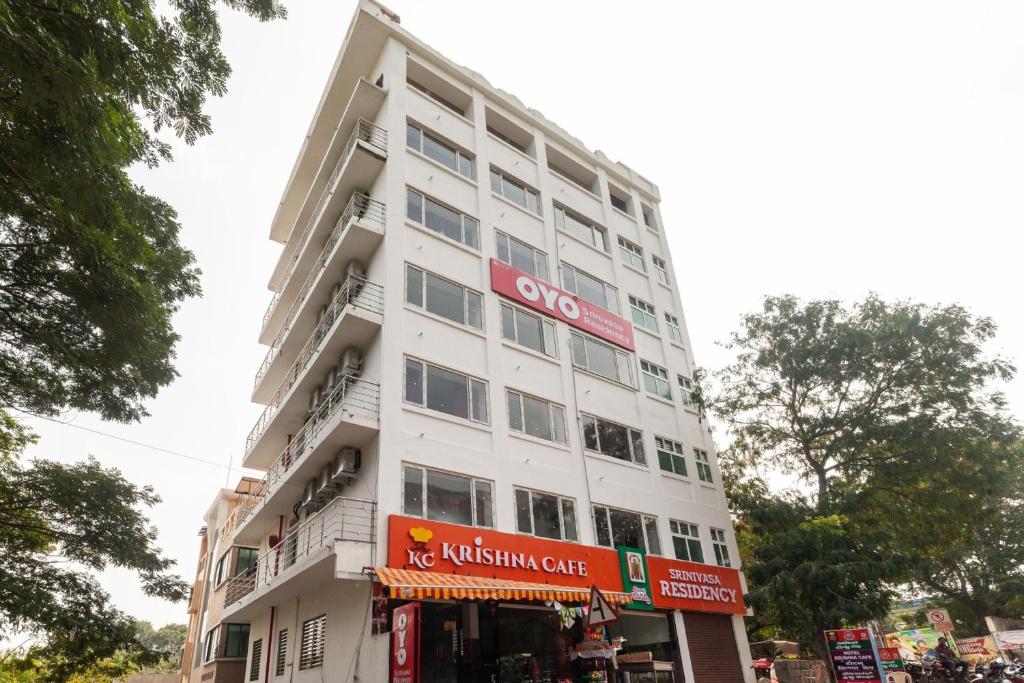 un edificio blanco con un cartel. en Capital O Hotel Srinivasa Residency en Tirupati