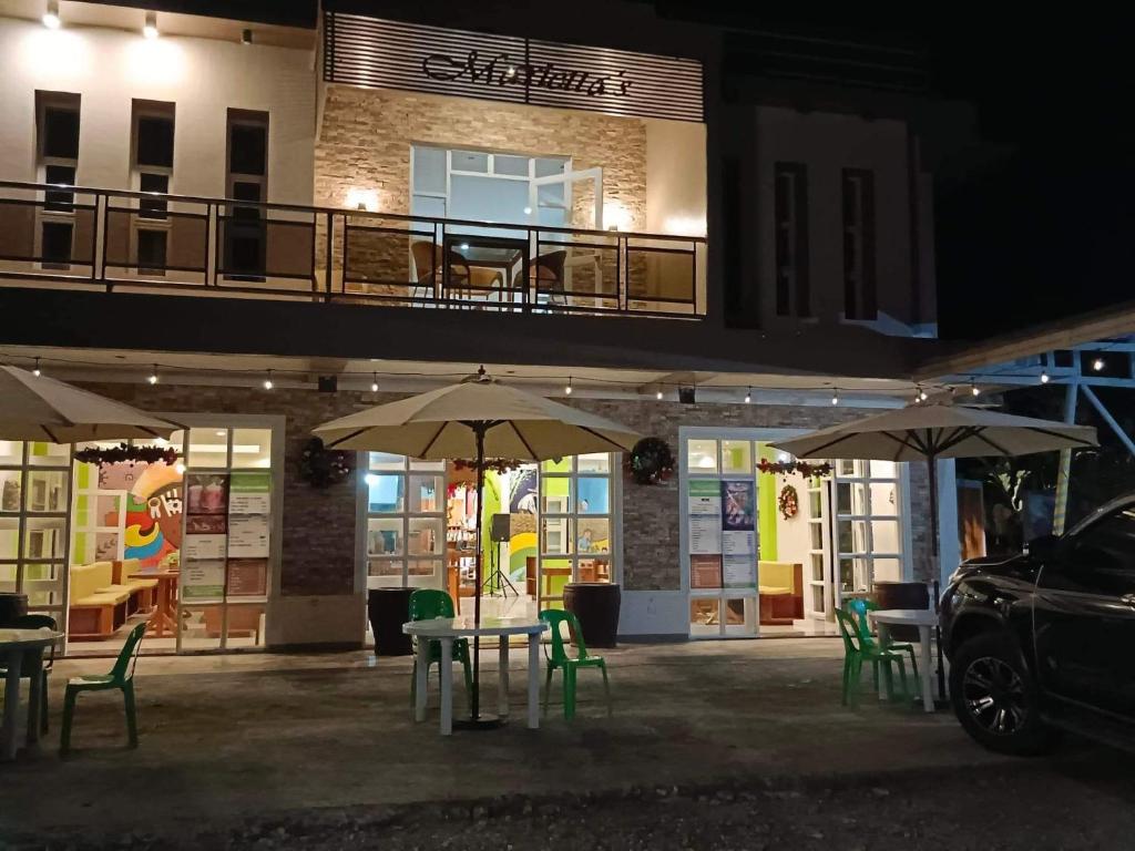 two tables and chairs with umbrellas in front of a building at Marietta's Hotel in Bajuyan
