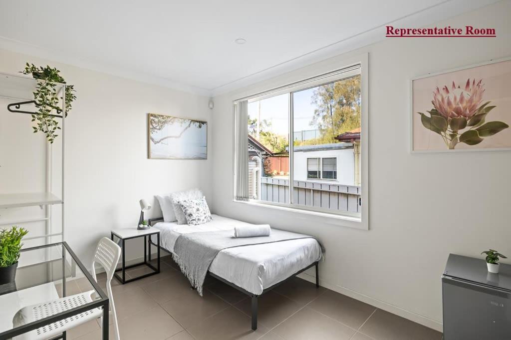 ein weißes Zimmer mit einem Bett und einem Fenster in der Unterkunft Cozy Single Room in Panania - Close to Station & Eateries - Shared Bathroom in Panania
