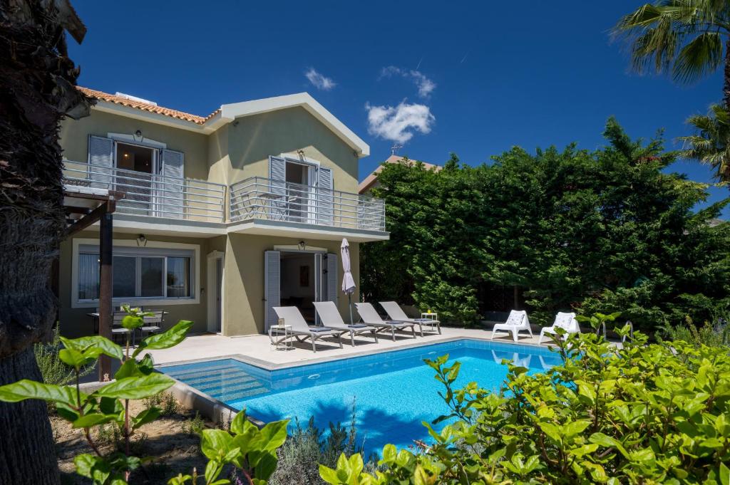 a villa with a swimming pool and a house at Beachfront Villa Alexandra in Skala Kefalonias