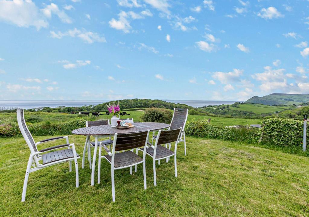 a table and chairs on the grass with a view at Easter Cottage - Berrynarbor in Berrynarbor