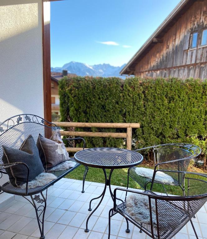 a patio with two chairs and a table and a bench at Haus Alpendomizil - Sommer-Bergbahnen kostenlos in Bolsterlang