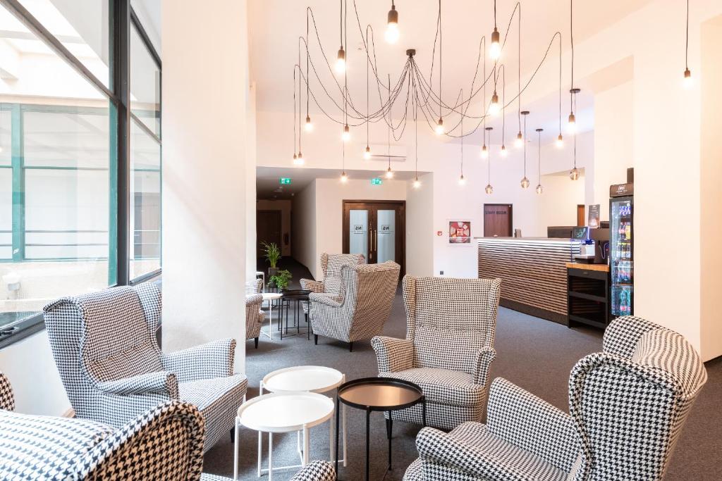 a waiting room with chairs and tables and a chandelier at Narodni Stay in Prague